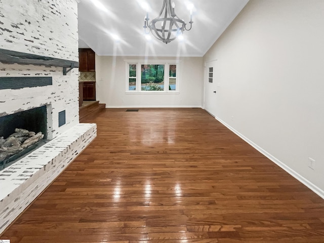 unfurnished living room featuring a fireplace, dark hardwood / wood-style flooring, vaulted ceiling, and an inviting chandelier