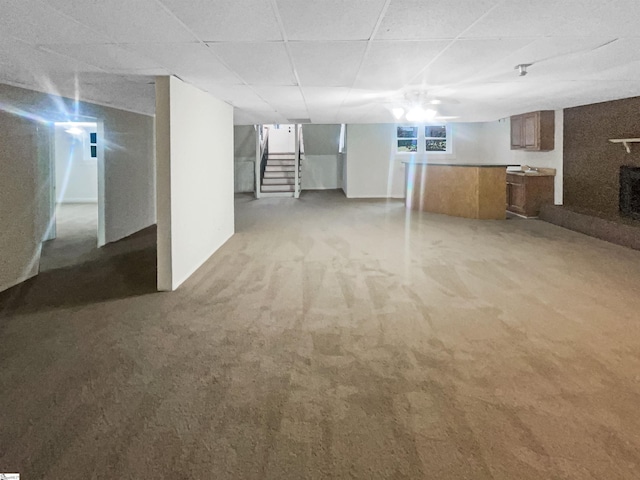 basement with carpet flooring, a paneled ceiling, and a fireplace