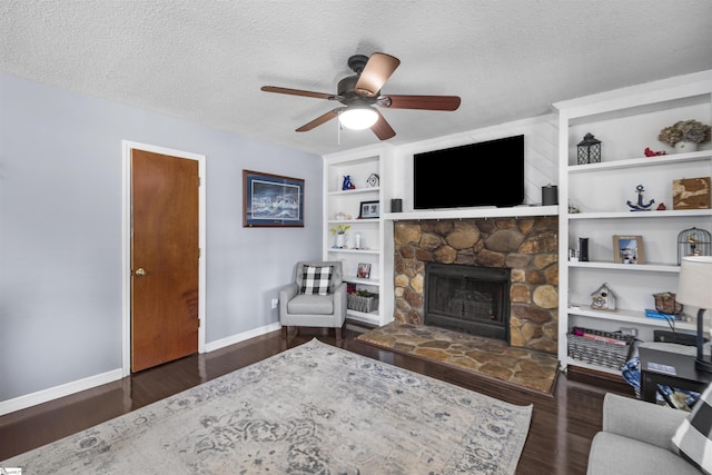 living room featuring a textured ceiling, a fireplace, ceiling fan, and dark wood-type flooring