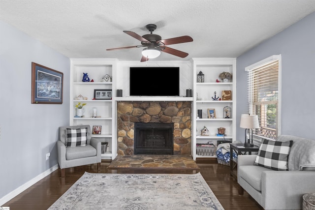 living room featuring a stone fireplace, ceiling fan, dark hardwood / wood-style floors, and a textured ceiling