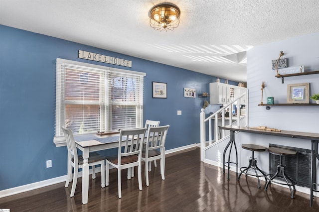 dining area featuring dark wood-type flooring and a textured ceiling