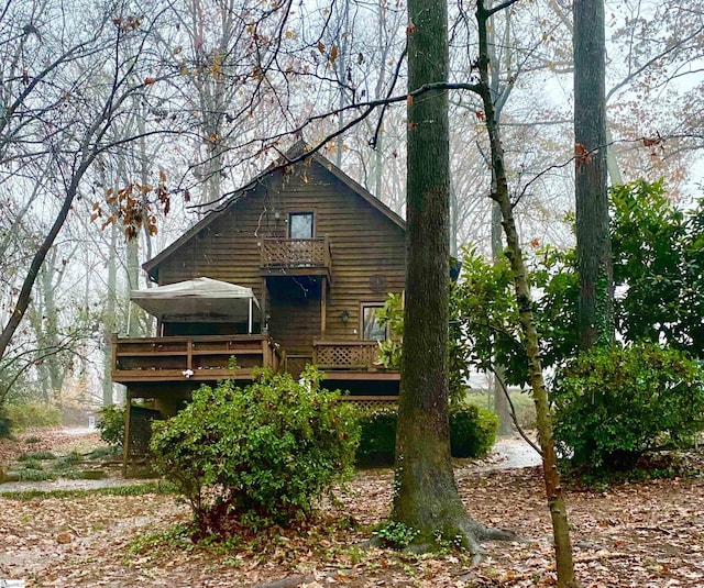 rear view of house featuring a balcony and a wooden deck