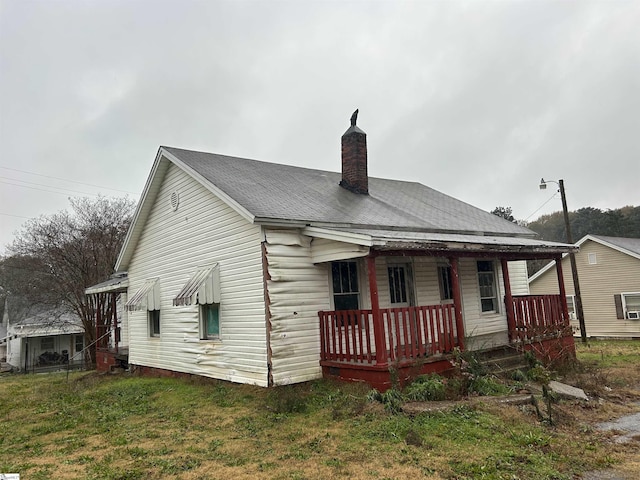 rear view of house featuring covered porch and a lawn