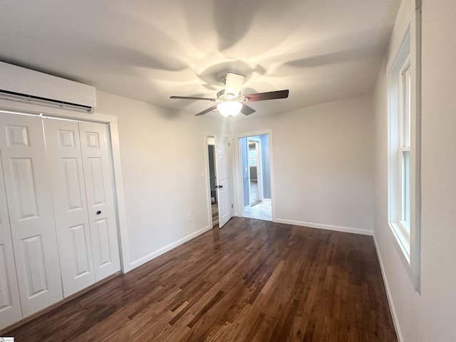 unfurnished bedroom with dark hardwood / wood-style flooring, a closet, a wall unit AC, and ceiling fan