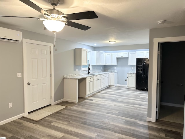 kitchen featuring white cabinetry, light stone countertops, black refrigerator with ice dispenser, a wall unit AC, and light wood-type flooring