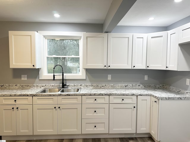 kitchen featuring white cabinets, light stone counters, sink, and dark wood-type flooring