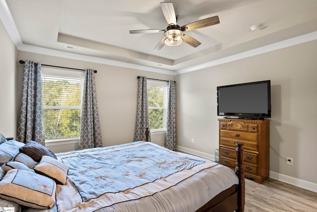 bedroom featuring a tray ceiling, ceiling fan, and light hardwood / wood-style flooring