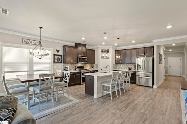 kitchen featuring dark brown cabinetry, hanging light fixtures, and stainless steel appliances