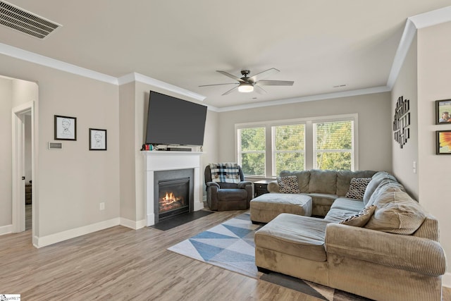 living room featuring light hardwood / wood-style flooring, ceiling fan, and crown molding