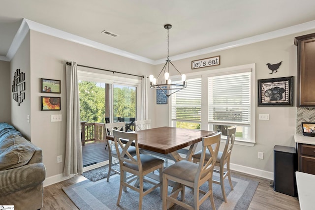 dining space with an inviting chandelier, a healthy amount of sunlight, and light wood-type flooring