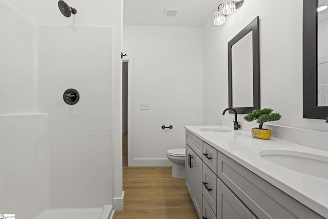 bathroom with hardwood / wood-style flooring, vanity, toilet, and walk in shower