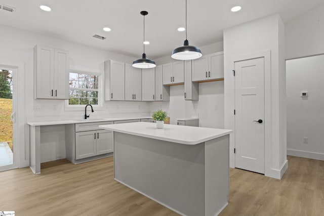 kitchen with sink, a center island, a healthy amount of sunlight, and light hardwood / wood-style floors