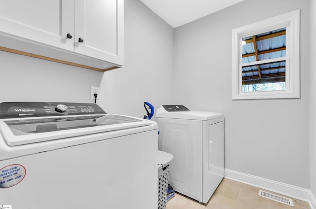 washroom featuring washer and clothes dryer, light tile patterned flooring, and cabinets