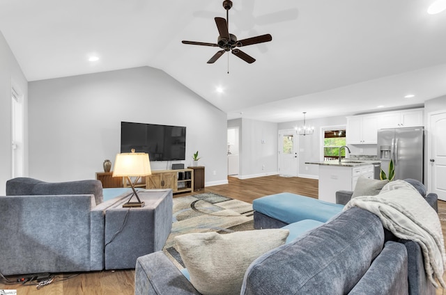 living room with dark hardwood / wood-style flooring, ceiling fan with notable chandelier, vaulted ceiling, and sink