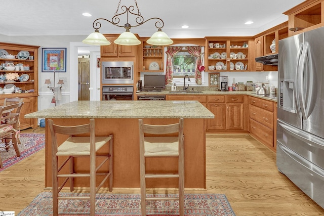 kitchen featuring a kitchen breakfast bar, sink, stainless steel appliances, and light hardwood / wood-style flooring