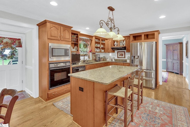 kitchen with a center island, sink, light hardwood / wood-style flooring, decorative light fixtures, and stainless steel appliances