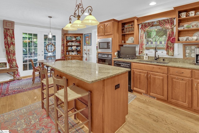 kitchen with a kitchen breakfast bar, black appliances, sink, light hardwood / wood-style flooring, and a center island