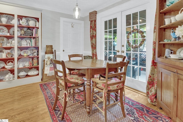 dining area featuring crown molding, light hardwood / wood-style flooring, and french doors