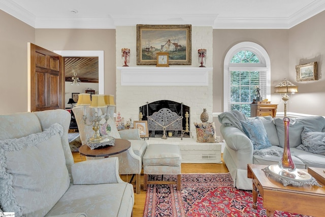 living room with crown molding, light hardwood / wood-style flooring, ceiling fan, and a brick fireplace