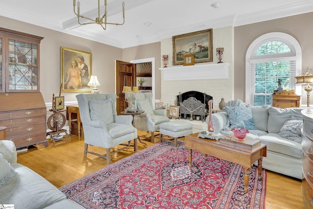 living room with crown molding, a fireplace, a chandelier, and light wood-type flooring