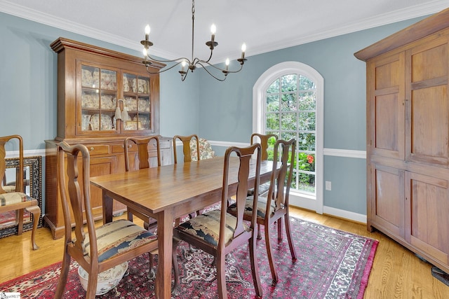 dining area featuring light hardwood / wood-style floors, ornamental molding, and a chandelier