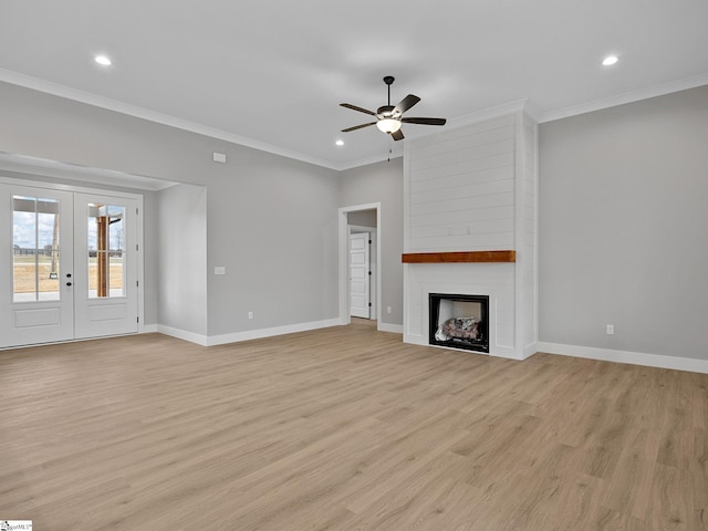 unfurnished living room with french doors, ceiling fan, light wood-type flooring, ornamental molding, and a large fireplace