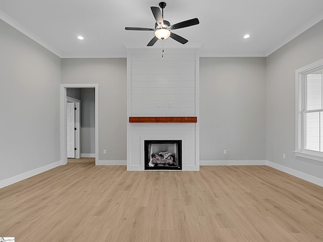 unfurnished living room with ceiling fan, a large fireplace, ornamental molding, and light hardwood / wood-style flooring