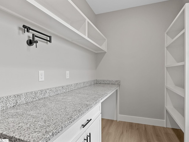 interior space featuring light stone countertops, light wood-type flooring, and white cabinetry