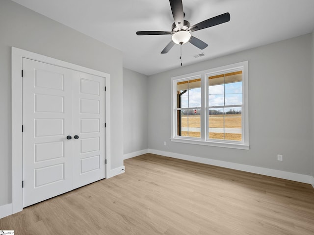 unfurnished bedroom with ceiling fan, a closet, and light wood-type flooring