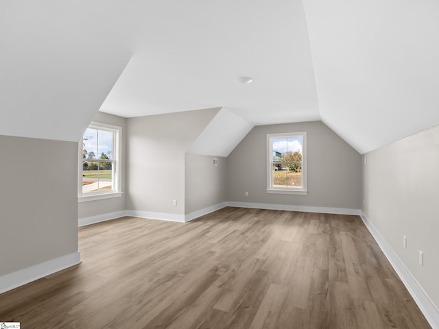 bonus room with light hardwood / wood-style floors and vaulted ceiling