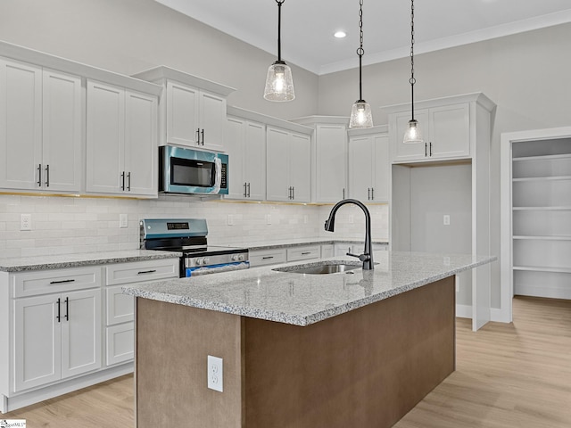 kitchen with white cabinets, appliances with stainless steel finishes, an island with sink, and sink