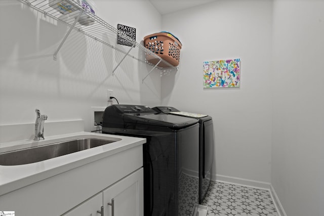 clothes washing area with cabinets, washer and clothes dryer, and sink