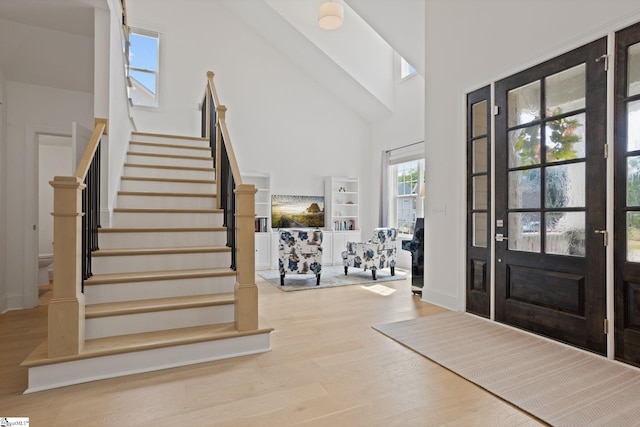 foyer with high vaulted ceiling and light hardwood / wood-style flooring