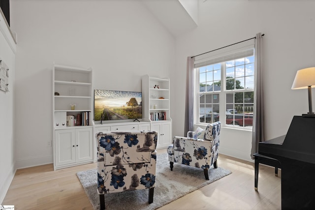 sitting room with high vaulted ceiling and light wood-type flooring