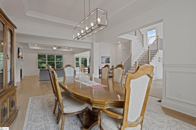 dining area featuring a chandelier, light hardwood / wood-style floors, crown molding, and a tray ceiling