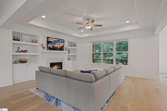 living room with ceiling fan, light wood-type flooring, a fireplace, and ornamental molding