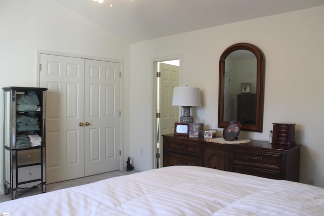 bedroom with a closet, light colored carpet, and lofted ceiling