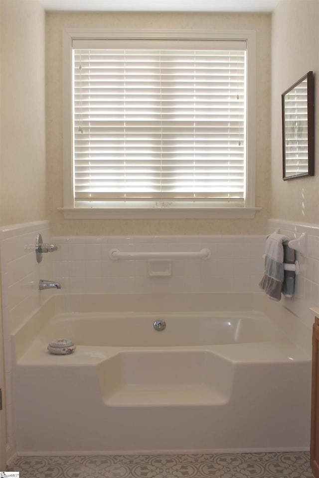 bathroom featuring tile patterned flooring, a washtub, vanity, and a wealth of natural light