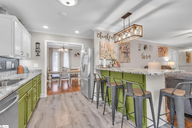 kitchen featuring appliances with stainless steel finishes, light wood-type flooring, a breakfast bar, green cabinetry, and white cabinets