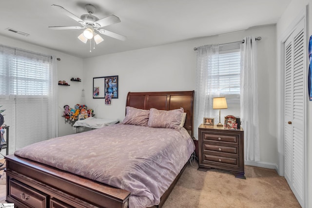 bedroom with ceiling fan, a closet, and light carpet