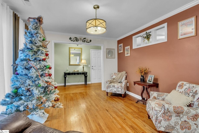 sitting room with hardwood / wood-style floors and crown molding