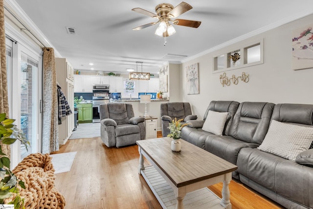 living room featuring light wood-type flooring, a wealth of natural light, crown molding, and ceiling fan