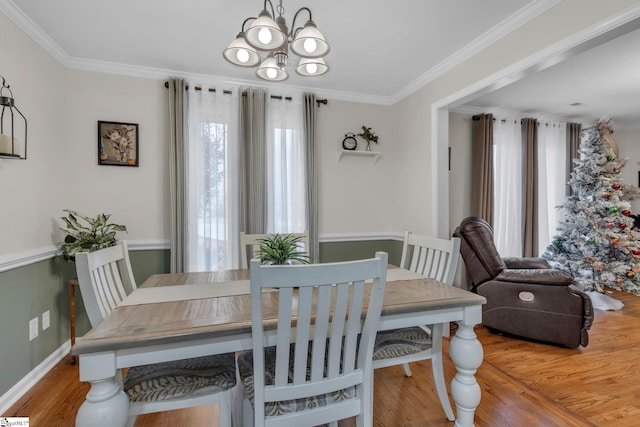 dining space featuring light wood-type flooring, an inviting chandelier, and crown molding