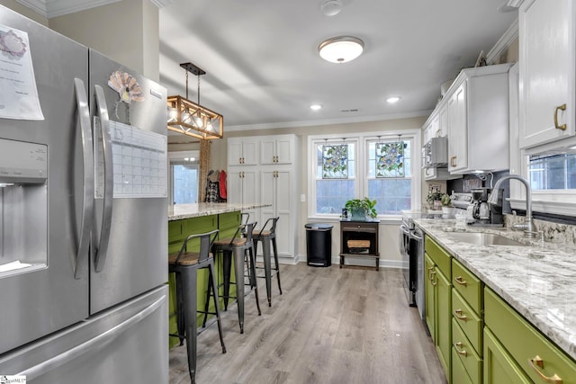 kitchen with light wood-type flooring, stainless steel appliances, sink, green cabinetry, and white cabinetry