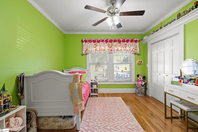 bedroom with a closet, ceiling fan, crown molding, and light wood-type flooring