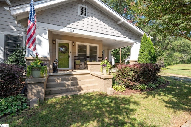 view of exterior entry with a yard and a porch