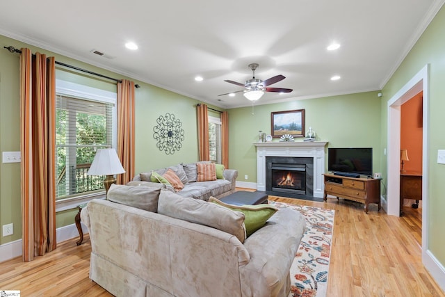 living room featuring light hardwood / wood-style flooring, ceiling fan, and crown molding