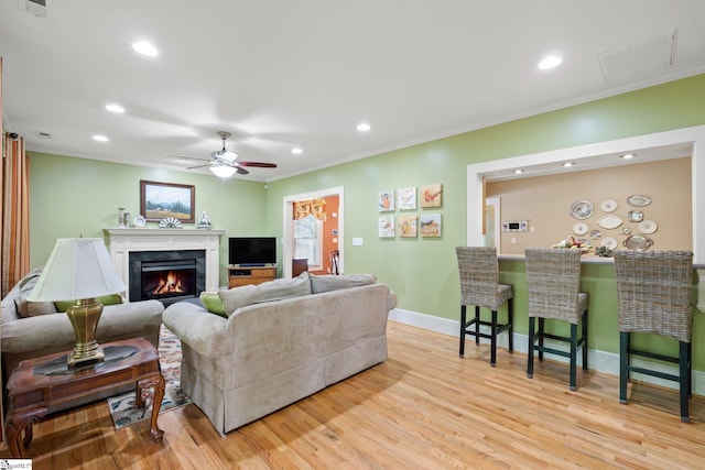 living room with crown molding, ceiling fan, and light hardwood / wood-style floors