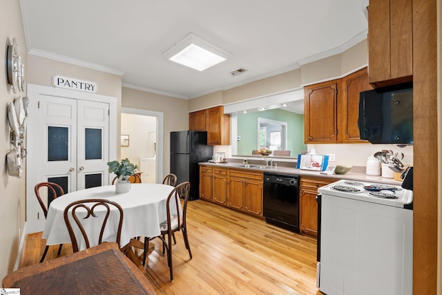 kitchen with washer / dryer, light wood-type flooring, crown molding, and black appliances