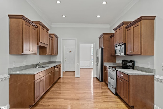 kitchen featuring ornamental molding, sink, light hardwood / wood-style flooring, and appliances with stainless steel finishes